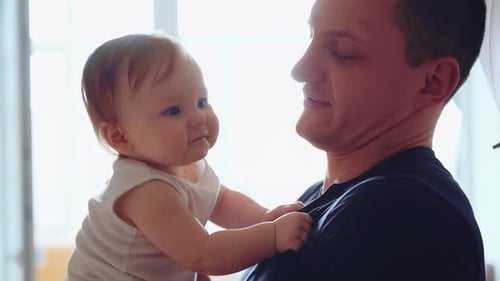 Father Holding Baby in Bright Indoor Setting