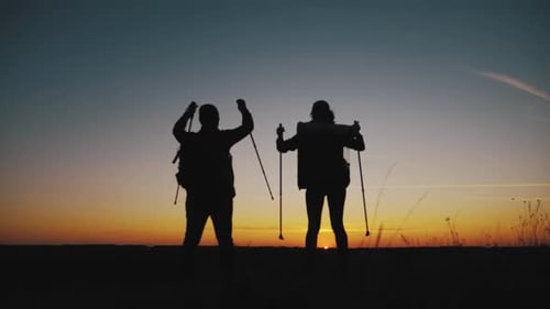 Happy Couple Man and Woman Tourist at Top of Mountain at Sunset Outdoors During a Hike. Silhouettes