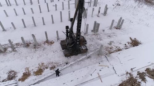 Construction Site in Winter with Excavator and Pillars