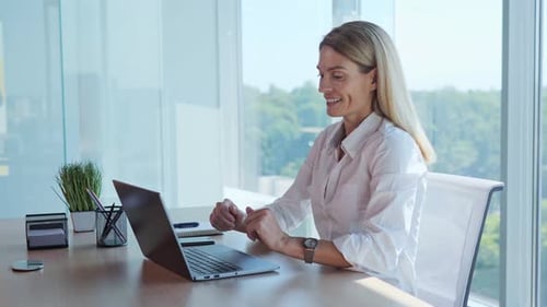 Smiling Woman Using Laptop at Office Desk