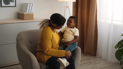 Woman Holding Child in Armchair at Home