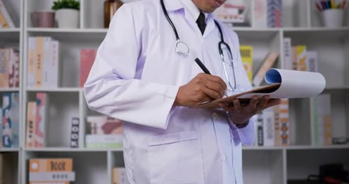 Medical Professional Writing on Clipboard in Office