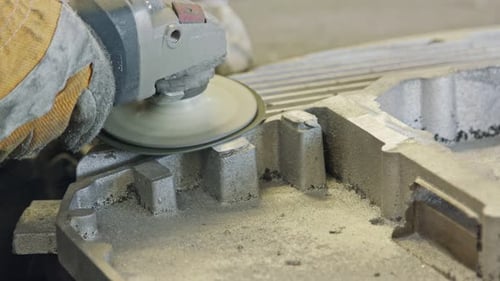 Klumpen der Hände eines Arbeiters beim Polieren eines Metallgussteils mit einer Schleifmaschine