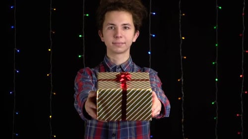 Young Adult Holds Out Birthday Gift Wrapped in Gold