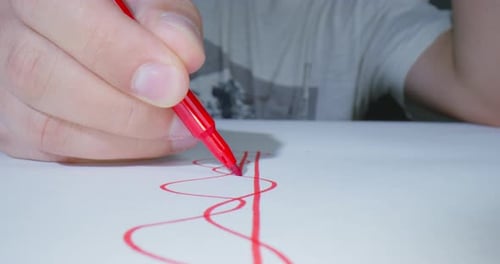Person zeichnet eine grafische Linie oder ein Muster für ein neues Projektdesign mit einem roten Filzstift, Vorderansicht, Makro