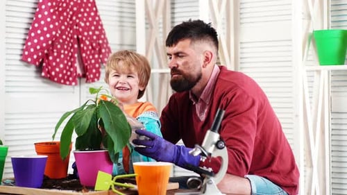 Middle Age Man and His Little Boy Watering Flowers in Pot Father and Son Plantig Plant.
