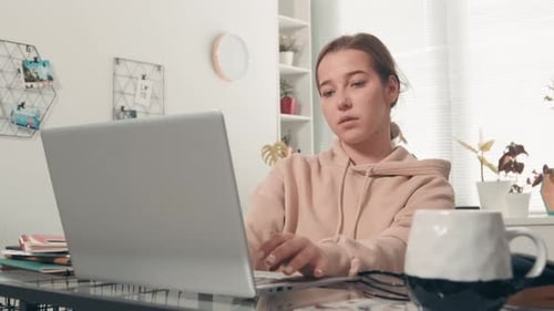 Estudiante femenina escribiendo en una computadora portátil en casa