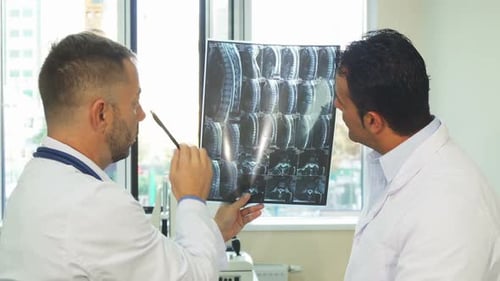 Doctors Reviewing Spinal X-Ray in Office Setting