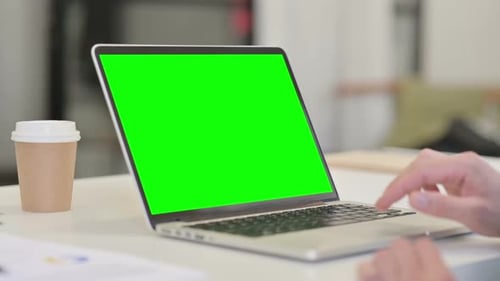 Laptop with Green Screen and Hand on Trackpad