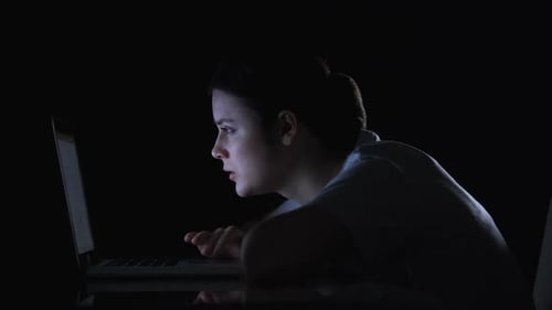 Woman Laughing at Laptop in Dark Room at Night