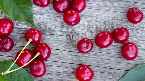 Reife, saftige rote Kirsche mit grünen Blättern liegt wie im Sommer auf einem alten, rissigen Holztisch