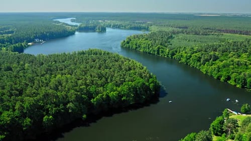 Small white boat on a river among forests, Poland