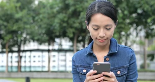 Woman Using Smartphone in an Urban Park Setting