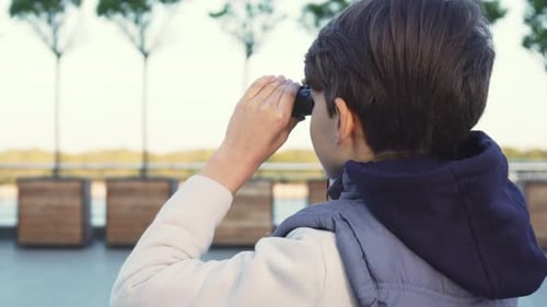 A Cute Boy Examines the Neighborhood Through Binoculars