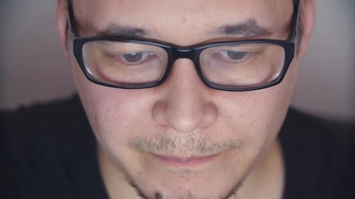 Front View of a Man in Glasses Browsing the Internet at Old Stylish Office at Night Time.