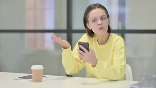 Woman Looks at Smartphone with Surprised Expression
