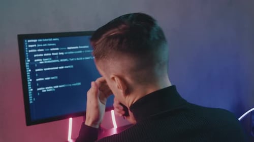 Back View Portrait of Tired IT Professional Programmer in Glasses Is Overworking on Computer