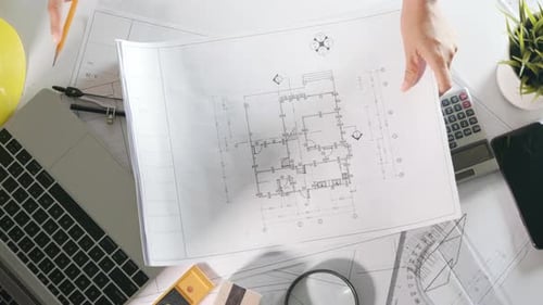 Architect open drawing paper to review and design of house editing with pencil on plan blueprint