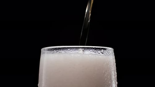 Foamy Drink Being Poured into Clear Glass