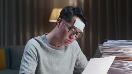 Close Up Of Sick Asian Man Tried While Working Hard With Documents At The Home