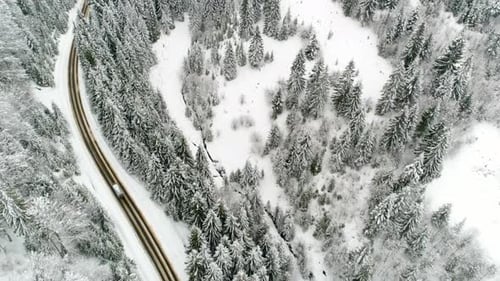AERIAL: Car Driving Along the Forest Road in Winter