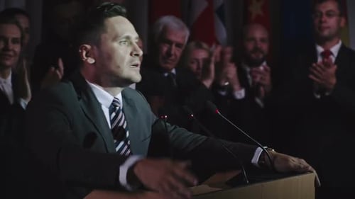 Man Giving Speech at Podium With Flags