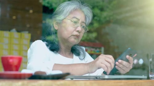 Senior Woman Using Smartphone at Table Indoors