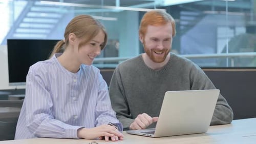 Smiling Team Discussing Project on Laptop in Modern Office