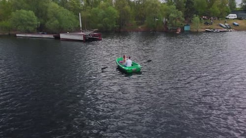 Aerial View of a Young Couple in Love Who is Riding a Rowboat on the River on a Summer Day