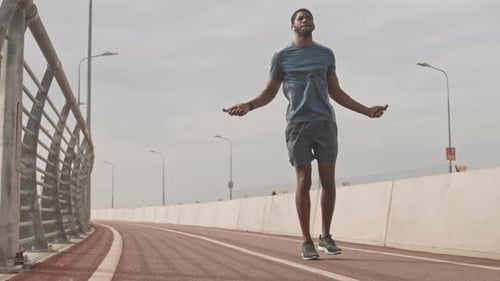 Athletic Man Jumping Rope On Bridge