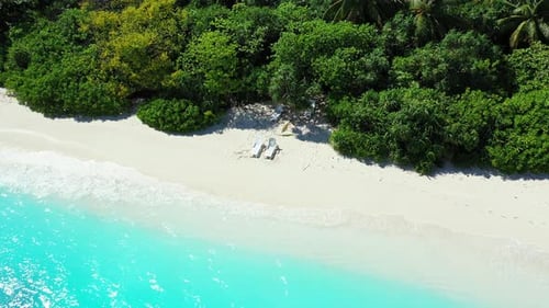 Daytime drone copy space shot of a sandy white paradise beach and aqua blue water background