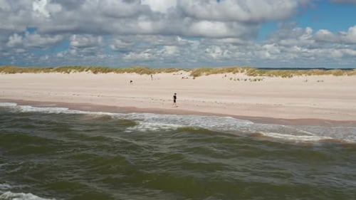 Fantastische Panoramaaufnahmen von einem Mann, der an einem sonnigen Tag am Sandstrand läuft