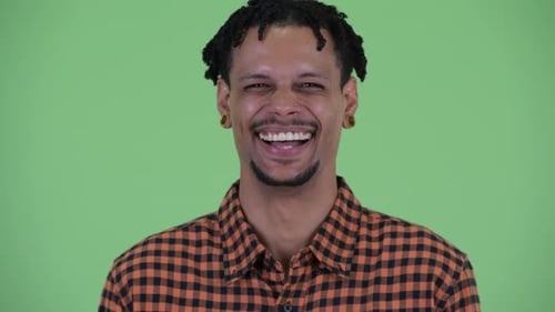 Gesicht eines glücklichen jungen gutaussehenden afrikanischen Mannes lächelnd und lachend