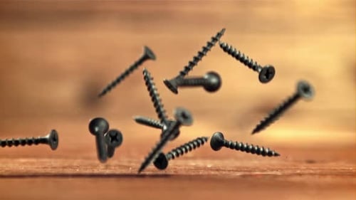 Black Screws Falling onto a Wooden Surface