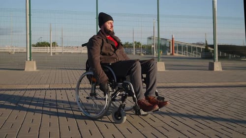 Man Wheeling Himself in a Wheelchair Outdoors