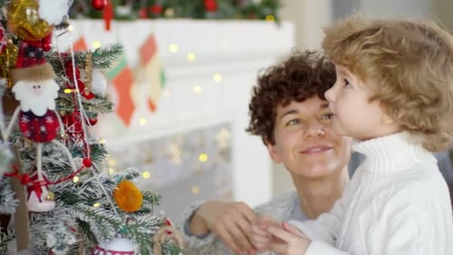 Kleiner Junge und seine Mutter schmücken den Weihnachtsbaum
