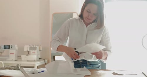Slow Motion Footage of the Fashion Designer Which Works at a Table with Curves and a Pattern She are