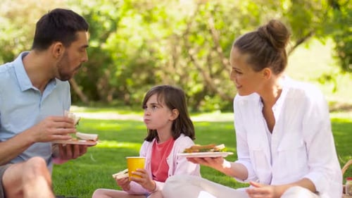 Family Eating Sandwiches on Picnic at Summer Park
