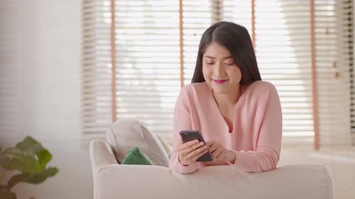 Woman Using Smartphone on Couch at Home