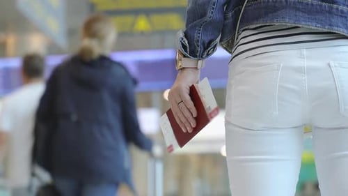 Woman Walks Through Airport Holding Passport