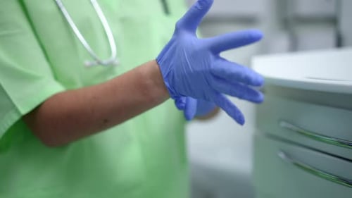 Hands of Unrecognizable Doctor Putting on Medical Gloves in Slow Motion Indoors