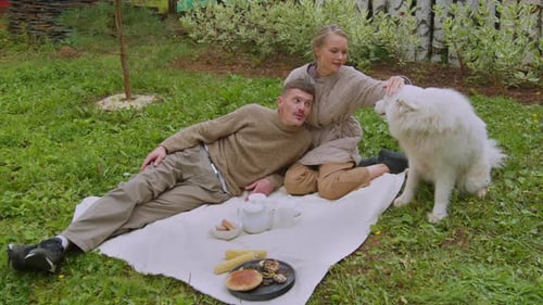 Couple Picnic on Grass with Large White Dog
