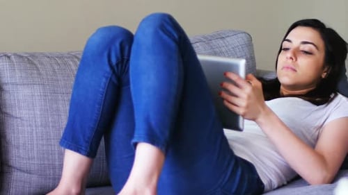 Woman Relaxing on Couch Using Tablet