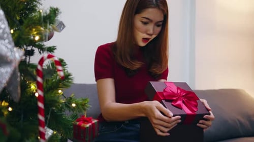 Excited Woman Opening Christmas Gift at Home