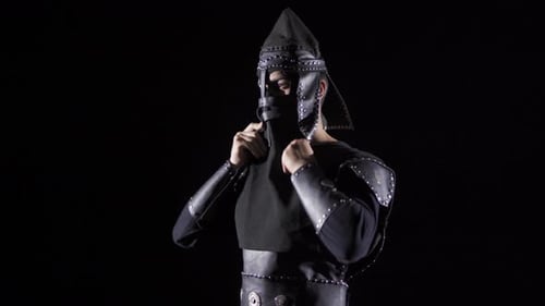 Man Putting on Leather Armor in Dark Studio