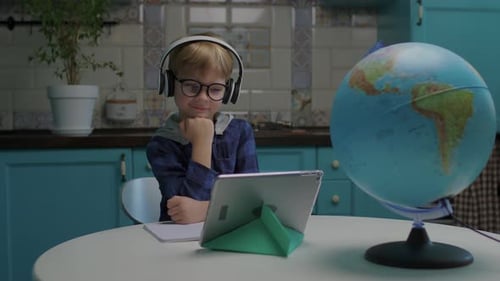 Preschool Kid Wearing Headphones Using Tablet Computer for Online Education or Watching Cartoons