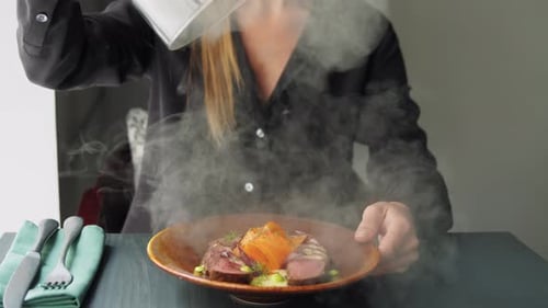 Waiter Serving Meat Dishes with Smoke To a Client in a Restaurant