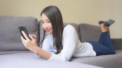 Woman Relaxing on Sofa Using Smartphone