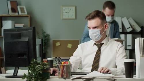 Workers Wearing Medical Protective Masks Working in Office Employee Sitting at Table Using Computer