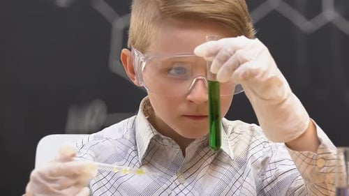 Schoolboy Adding Liquid Into Test Tube With Green Substance, Observing Reaction